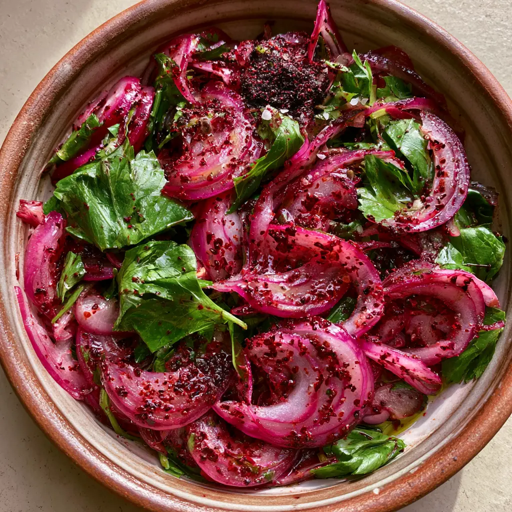 Turkish Onion Salad Recipe: Authentic Sumac Onions (Sumaklı Soğan) 2 Top-down view of massaged red onion half-moons stained with grainy sumac and fresh parsley leaves. (Turkish onion salad)