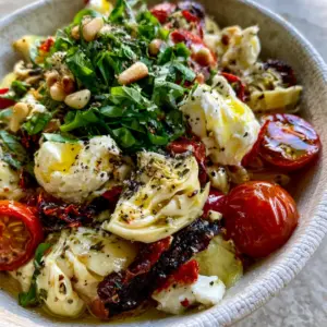 Extreme close-up of marinated artichoke hearts and sun-dried tomatoes in a Tuscan artichoke tomato salad.