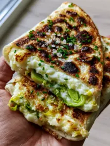 Close up of a crispy toasted leek and potato wrap with charred leopard spots and fresh chives. (leek and potato wraps)